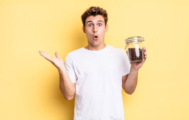 Şaşırmış ve şoke olmuş bir halde, çenesi düşmüş ve eli açık bir objeyi tutuyordu. kahve çekirdeği konsepti