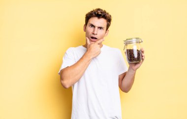 Ağzı ve gözleri sonuna kadar açık ve elleri çenesinde, hoş olmayan bir şokta, ne ya da vay canına diyor. kahve çekirdeği konsepti