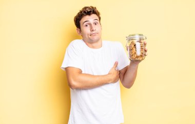 Omuz silkme, şaşkın ve kararsız hissetme, kolları çapraz ve şaşkın bakışlarla şüpheye düşme. Ev yapımı kurabiye konsepti