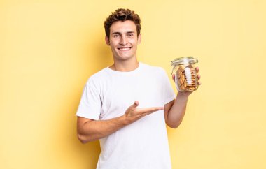 Neşeli bir şekilde gülümseyen, mutlu hisseden ve fotokopi uzayında avucunun içinde bir konsept gösteren. Ev yapımı kurabiye konsepti