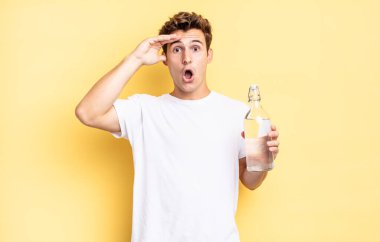 Mutlu, şaşkın ve şaşırmış görünüyor, gülümsüyor ve inanılmaz ve inanılmaz iyi haberleri fark ediyor. su şişesi kavramı