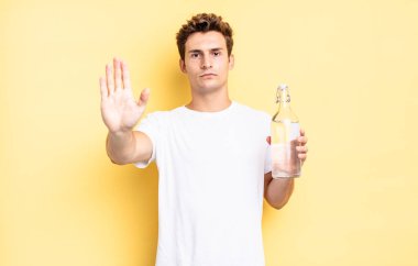 Ciddi görünüyor, sert, hoşnutsuz ve kızgın. Avuç içini açıp durmasını gösteriyor. su şişesi kavramı