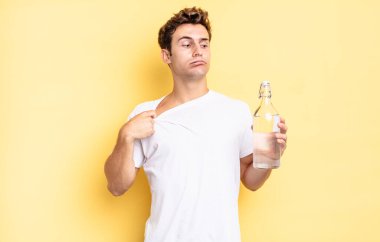 Stresli, endişeli, yorgun ve hayal kırıklığına uğramış, gömleğini çekmiş, sorunlu görünüyor. su şişesi kavramı