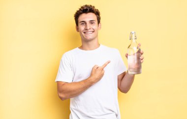 Neşeli bir şekilde gülümseyen, mutlu hisseden, kenarı ve yukarıyı gösteren, fotokopi uzayındaki nesneleri gösteren. su şişesi kavramı