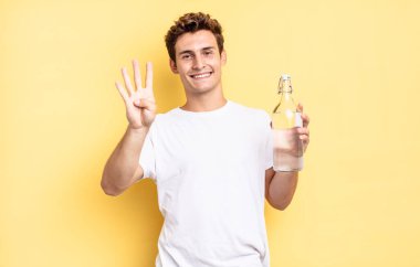 Gülümsüyor ve dost canlısı görünüyor, 4 ya da 4 numarayı gösteriyor, elle ileri doğru sayıyor, geri sayıyor. su şişesi kavramı