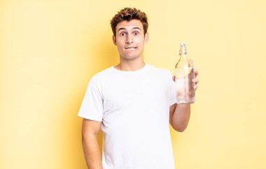 Şaşırmış ve kafası karışmış görünüyor, sinirsel bir hareketle dudağını ısırıyor, sorunun cevabını bilmiyor. su şişesi kavramı