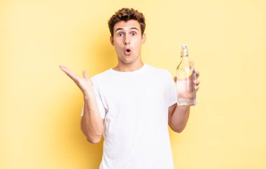 Şaşırmış ve şoke olmuş bir halde, çenesi düşmüş ve eli açık bir objeyi tutuyordu. su şişesi kavramı