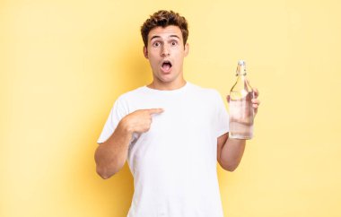 Şok olmuş ve ağzı açık, kendini işaret ederek şaşırmış görünüyordu. su şişesi kavramı