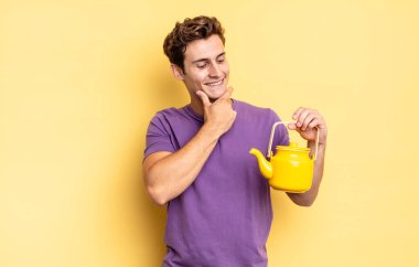 Mutlu, kendinden emin bir ifadeyle gülümsüyor, çenesinde elle, merakla yan tarafa bakıyor. çaydanlık konsepti