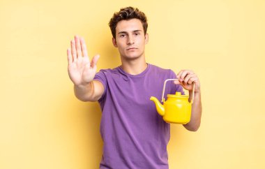 Ciddi görünüyor, sert, hoşnutsuz ve kızgın. Avuç içini açıp durmasını gösteriyor. çaydanlık konsepti