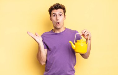 Şaşırmış ve şoke olmuş bir halde, çenesi düşmüş ve eli açık bir objeyi tutuyordu. çaydanlık konsepti