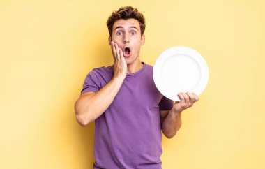 Şok olmuş ve korkmuş hissediyorum, ağzı açık ve elleri yanaklarında korkmuş görünüyor. boş tabak kavramı