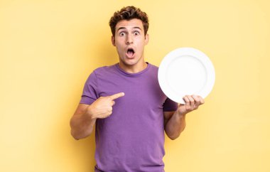 Şok olmuş ve ağzı açık, kendini işaret ederek şaşırmış görünüyordu. boş tabak kavramı