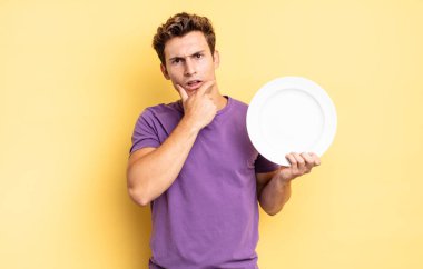 Ağzı ve gözleri sonuna kadar açık ve elleri çenesinde, hoş olmayan bir şokta, ne ya da vay canına diyor. boş tabak kavramı