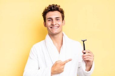 Neşeli bir şekilde gülümseyen, mutlu hisseden, kenarı ve yukarıyı gösteren, fotokopi uzayındaki nesneleri gösteren. traş konsepti