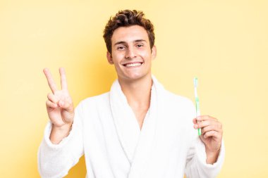 Gülümseyen ve mutlu görünen, kaygısız ve pozitif, tek elle zafer ya da barış işareti yapan. diş fırçası konsepti