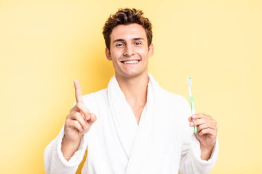 Gururla ve kendinden emin bir şekilde gülümseyerek bir numaralı pozu vererek, bir lider gibi hissederek. diş fırçası konsepti