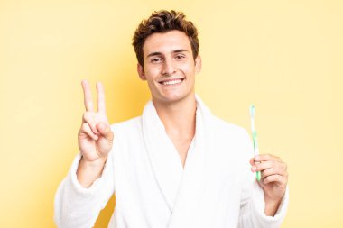 Gülümsüyor ve dost canlısı görünüyor. İki ya da iki numarayı gösteriyor. Elini ileri uzatıp geri sayıyor. diş fırçası konsepti