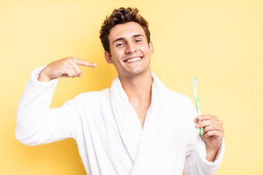 Kendi geniş gülüşüne, pozitif, rahat, tatmin olmuş tavrına güvenerek gülümsüyor. diş fırçası konsepti