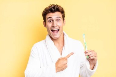 Heyecanlı ve şaşırmış görünüyor. Yana doğru ve yukarı doğru uzayı gösteriyor. diş fırçası konsepti