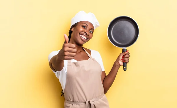 black afro chef woman feeling proud, carefree, confident and happy, smiling positively with thumbs up