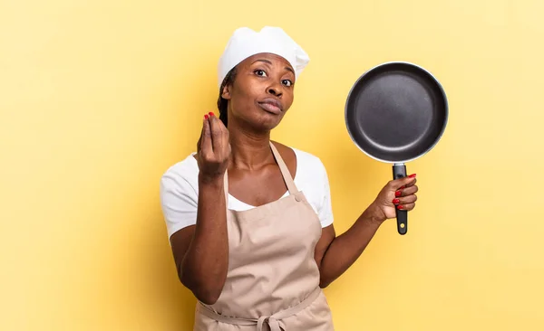 black afro chef woman making capice or money gesture, telling you to pay your debts!
