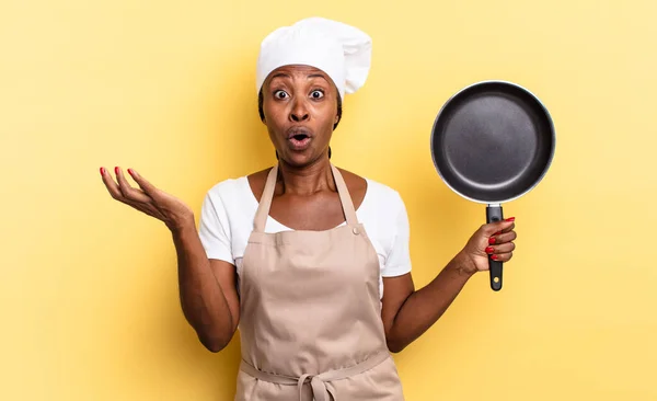 black afro chef woman open-mouthed and amazed, shocked and astonished with an unbelievable surprise