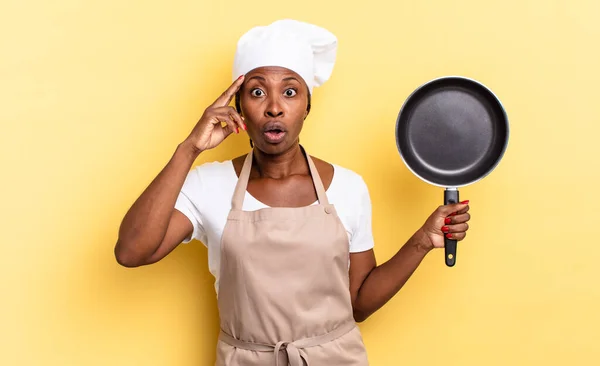 black afro chef woman looking surprised, open-mouthed, shocked, realizing a new thought, idea or concept