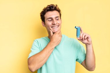 Mutlu, kendinden emin bir ifadeyle gülümsüyor, çenesinde elle, merakla yan tarafa bakıyor. astım konsepti