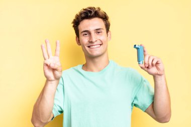 Gülümsüyor ve dost canlısı görünüyor. Üç ya da üç numarayı gösteriyor. Elleri önde, geriye doğru sayıyor. astım konsepti