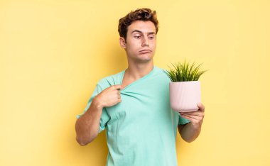 Stresli, endişeli, yorgun ve hayal kırıklığına uğramış, gömleğini çekmiş, sorunlu görünüyor. dekoratif bitki konsepti