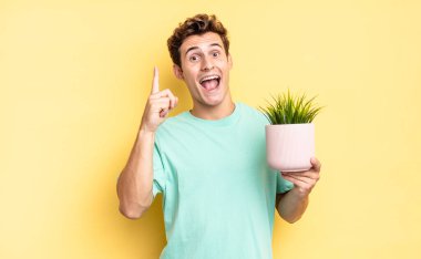Bir fikri fark ettikten sonra mutlu ve heyecanlı bir dahi gibi hissetmek, neşeli bir şekilde parmak kaldırmak, eureka! dekoratif bitki konsepti