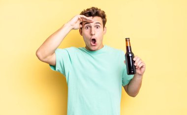 Mutlu, şaşkın ve şaşırmış görünüyor, gülümsüyor ve inanılmaz ve inanılmaz iyi haberleri fark ediyor. bira şişesi konsepti