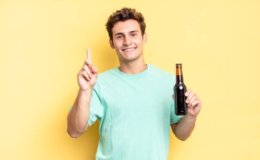 Gülümsüyor ve dost canlısı görünüyor, bir numara ya da ilk eli önde, geriye doğru sayıyor. bira şişesi konsepti