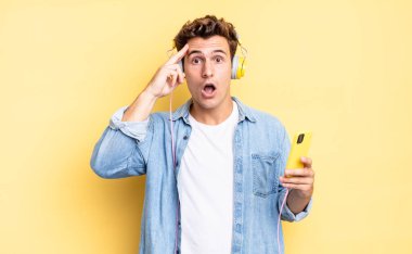 Şaşırmış, ağzı açık, şok olmuş, yeni bir düşünce, fikir ya da konseptin farkına varıyor. kulaklıklar ve akıllı telefon konsepti
