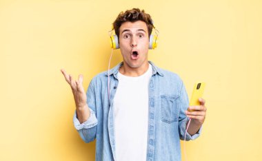 Son derece şok olmuş ve şaşırmış, endişeli ve paniklemiş hissediyorum, stresli ve dehşete düşmüş bir bakışla. kulaklıklar ve akıllı telefon konsepti