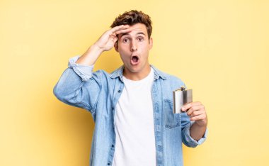 Mutlu, şaşkın ve şaşırmış görünüyor, gülümsüyor ve inanılmaz ve inanılmaz iyi haberleri fark ediyor. alkol şişesi konsepti