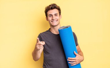 Tatmin olmuş, kendine güvenen, dostça gülümseyen ve seni seçen bir kameraya. yoga mat konsepti