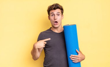 Şok olmuş ve ağzı açık, kendini işaret ederek şaşırmış görünüyordu. yoga mat konsepti