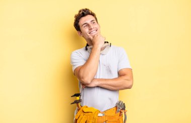 Mutlu, kendinden emin bir ifadeyle gülümsüyor, çenesinde elle, merakla yan tarafa bakıyor. Becerikli adam kavramı