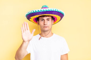 Ciddi görünüyor, sert, hoşnutsuz ve kızgın. Avuç içini açıp durmasını gösteriyor. Meksika şapkası konsepti
