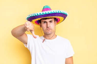 Kızgın, sinirli, hayal kırıklığına uğramış ya da hoşnutsuz, ciddi bir bakışla başparmaklarını aşağı gösteren. Meksika şapkası konsepti