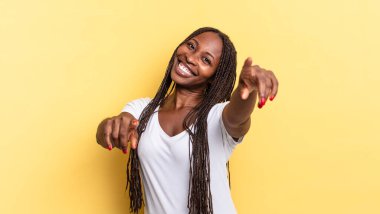 Afro siyah güzel bir kadın mutlu ve kendinden emin hissediyor, kamerayı iki eliyle gösteriyor ve gülüyor, seni seçiyor.