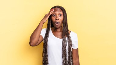 Afro siyah güzel kadın mutlu, şaşkın ve şaşırmış görünüyor, gülümsüyor ve inanılmaz ve inanılmaz iyi haberleri fark ediyor.