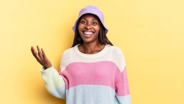 Afro siyah güzel bir kadın mutlu, şaşırmış ve neşeli, pozitif bir tavırla gülümseyen, bir çözüm ya da fikir gerçekleştiren
