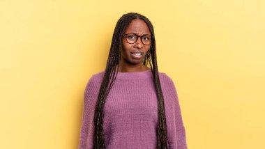 afro black pretty woman feeling puzzled and confused, with a dumb, stunned expression looking at something unexpected
