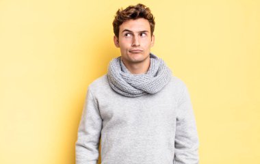 Genç çocuk şaşkın ve şaşkın görünüyor, merak ediyor ya da bir sorunu çözmeye çalışıyor ya da düşünüyor.