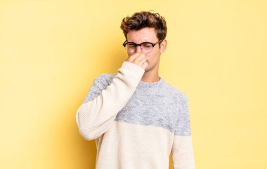 Delikanlı tiksiniyor, pis ve nahoş bir koku duymamak için burnunu tutuyor.