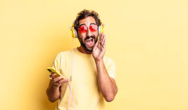 Mutlu hisseden, elleri ağızlarının yanında kulaklıkla bağıran çılgın bir adam.