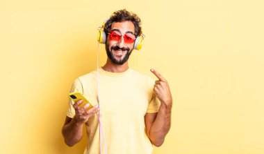 Yüzünde kulaklıkla kendi gülümsemesini işaret eden, güler yüzlü çılgın bir adam.